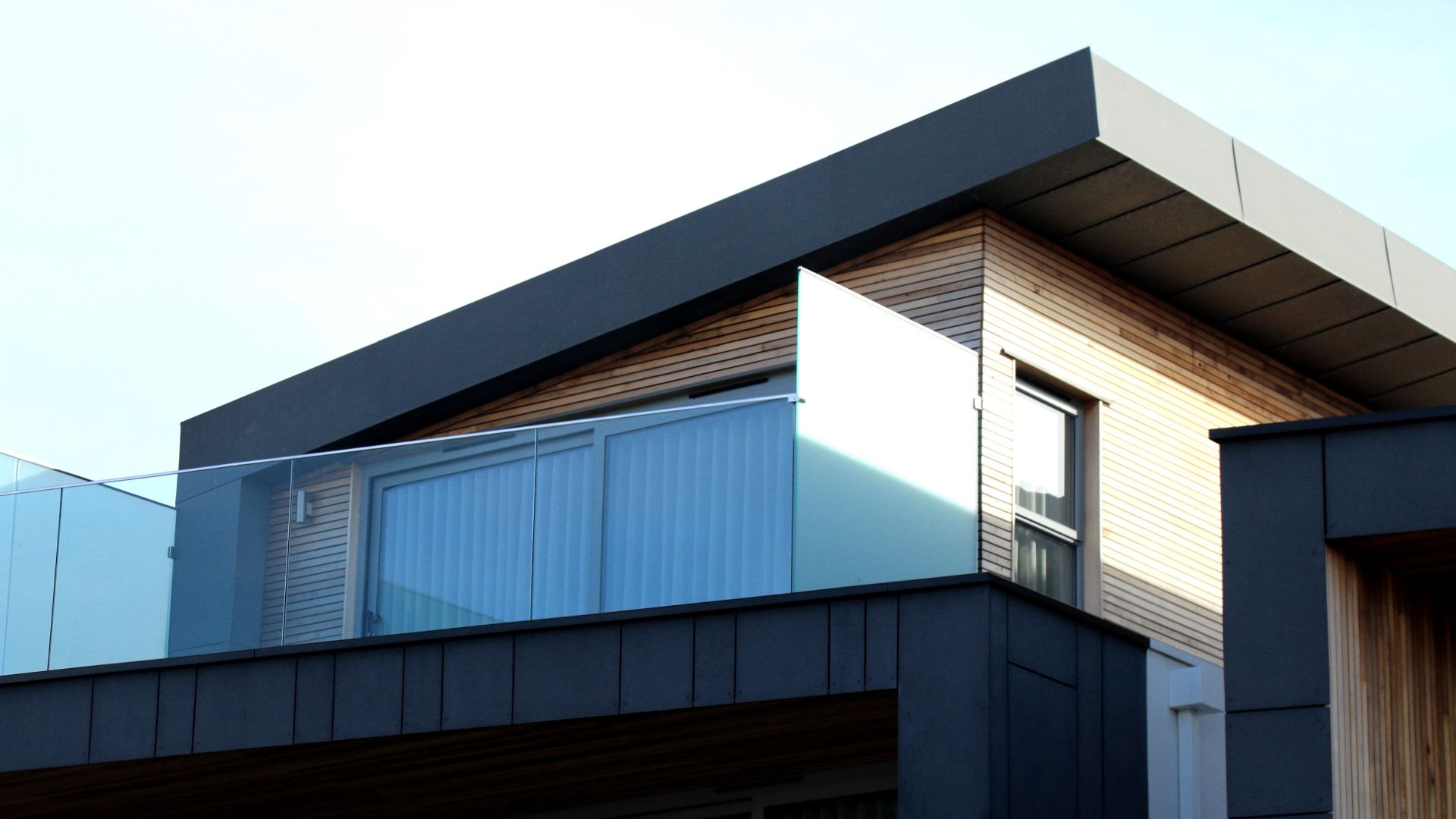 balcón moderno con cristal en vivienda acabados negro y madrera concepto espacio de vida diseño