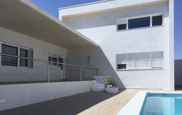 Exterior de vivienda moderna con doble altura en forma de L con piscina