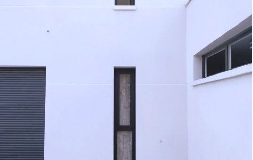 Exterior de vivienda con pared blanca con ventana y puerta negra